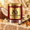 MAISON NOOR Ambered Vanille red glass candle with gold lid, styled with coconut, vanilla pods, jasmine and amber-colored resin on ivory stone.