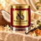MAISON NOOR Ambered Vanille red glass candle with gold lid, styled with coconut, vanilla pods, jasmine and amber-colored resin on ivory stone.