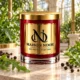 MAISON NOOR Arugula Element red glass candle with gold lid, styled with fresh green arugula leaves and black peppercorns in a sunlit conservatory.