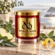 MAISON NOOR Baltic Dew red glass candle with gold lid, styled with dewy eucalyptus, sage, green apple and lemon peel beside a misty sea.