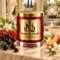 MAISON NOOR Black Currant and Jasmine red glass candle with gold lid, styled with black and red currants, jasmine, peach and black tea in a garden pavilion.