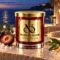 MAISON NOOR Black Sea red glass candle with gold lid, styled with plum, eucalyptus, citrus leaves and sea salt on an ivory terrace at blue hour.