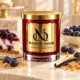 MAISON NOOR Blueberry Cheesecake red glass candle with gold lid, styled with blueberry cheesecake, blueberries, graham cracker crumbs and vanilla on ivory stone.
