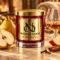 MAISON NOOR Brandied Pear red glass candle with gold lid, styled with pear, apple, cinnamon, cloves and a crystal brandy glass in a warm luxury lounge.