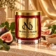 MAISON NOOR Brown Sugar and Fig red glass candle with gold lid, styled with ripe figs, fig leaves, brown sugar and sea salt on ivory stone.