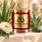 MAISON NOOR Cactus Flower and Jade red glass candle with gold lid, styled with aloe, agave, white chrysanthemum and jade-green stone in a desert spa.