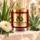 MAISON NOOR Cactus Flower and Jade red glass candle with gold lid, styled with aloe, agave, white chrysanthemum and jade-green stone in a desert spa.