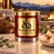 MAISON NOOR Campfire Marshmallow red glass candle with gold lid, styled with toasted marshmallows, eucalyptus and oak on a luxury lodge terrace at dusk.
