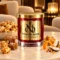 MAISON NOOR Caramel Popcorn red glass candle with gold lid, styled with caramel popcorn, praline, sea salt, orange peel and coconut in a luxury lounge.