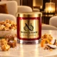 MAISON NOOR Caramel Popcorn red glass candle with gold lid, styled with caramel popcorn, praline, sea salt, orange peel and coconut in a luxury lounge.