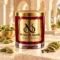 MAISON NOOR Cardamom Element red glass candle with gold lid, styled with green cardamom pods and seeds on ivory stone in a warm spice atelier.