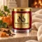 MAISON NOOR Cashmere Pumpkin red glass candle with gold lid, styled with pumpkin, vine leaves, cinnamon, cloves and caramel against cream cashmere.