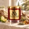 MAISON NOOR Cedarwood Blanc red glass candle with gold lid, styled with pale cedarwood, oakmoss, bergamot and amber resin on ivory stone.