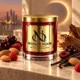 MAISON NOOR Cherry Eclipse red glass candle with gold lid, styled with black cherries, almonds, raspberries, vanilla and wood against warm eclipse-like lighting.