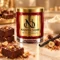 MAISON NOOR Chocolate Fudge red glass candle with gold lid, styled with chocolate fudge, hazelnuts, praline, vanilla and cream on ivory stone.