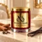 MAISON NOOR Cinnamon and Vanilla red glass candle with gold lid, styled with cinnamon sticks, cloves, vanilla pods and cream on ivory limestone.
