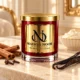 MAISON NOOR Cinnamon and Vanilla red glass candle with gold lid, styled with cinnamon sticks, cloves, vanilla pods and cream on ivory limestone.