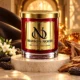 Red MAISON NOOR candle with gold lid on an ivory pedestal beside jasmine, tonka beans and sandalwood in warm amber light.