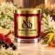 Red MAISON NOOR candle with gold lid beside elderflowers, tuberose, ylang-ylang, apple, raspberries and blackcurrants.