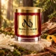 Red MAISON NOOR candle with gold lid on ivory stone beside enoki mushrooms, moss, wood and citrus peel in a forest setting.
