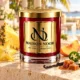 Red MAISON NOOR candle with gold lid beside pineapple, starfruit, peach, jalapeno, vanilla and caramel in a tropical terrace setting.