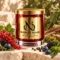 Red MAISON NOOR candle with gold lid beside red currants, blackberries, blueberries, peppercorns and moss on ivory stone.