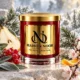 Red MAISON NOOR candle with gold lid beside frosted evergreen foliage, pear, red currants, sage, cherry blossom and citrus peel.