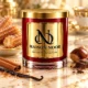 Red MAISON NOOR candle with gold lid beside churros, cinnamon, vanilla, chestnut and chocolate on ivory marble.