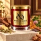 Red MAISON NOOR candle with gold lid beside wood, ginger, cardamom, fennel, lavender and pink clover on ivory stone.