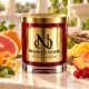 Red MAISON NOOR candle with gold lid beside grapefruit, orange peel, mango, peach, red currants and cedar wood on ivory stone.
