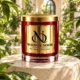 Red MAISON NOOR candle with gold lid on an ivory pedestal surrounded by fresh green leaves in a sunlit conservatory.