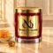 Red MAISON NOOR candle with gold lid on ivory stone beside honeycomb, honey and a gold honey dipper.