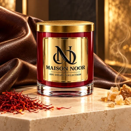 Red MAISON NOOR candle with gold lid on ivory stone beside saffron and incense resin, with rich brown leather draped behind.