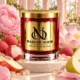 Red MAISON NOOR candle with gold lid beside lychees, apple, pear, pink peony, lotus flower and sugar crystals on ivory stone.