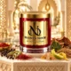 Red MAISON NOOR candle with gold lid beside peppercorns, cardamom, saffron, paprika, incense resin, bergamot peel, vetiver and tobacco leaves in a refined riad setting.