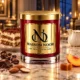Red MAISON NOOR candle with gold lid beside tiramisu, coffee beans, chocolate, almonds, peach and caramel, with a cream pitcher in a midnight salon.