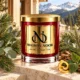 Red MAISON NOOR candle with gold lid beside pine, eucalyptus, evergreen foliage, cedar, patchouli leaf and citrus peel overlooking alpine mountains.