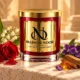 MAISON NOOR red and gold Nag Champa candle on limestone with rose, lily of the valley, violets and sandalwood in warm light.