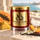 MAISON NOOR Papaya Paradise candle with papaya, pineapple, coconut, peach, lily of the valley and vanilla beside a turquoise lagoon.